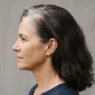 Side view of a woman in her fifties showing stark demarcation line between silver root regrowth and dark brown dyed lengths