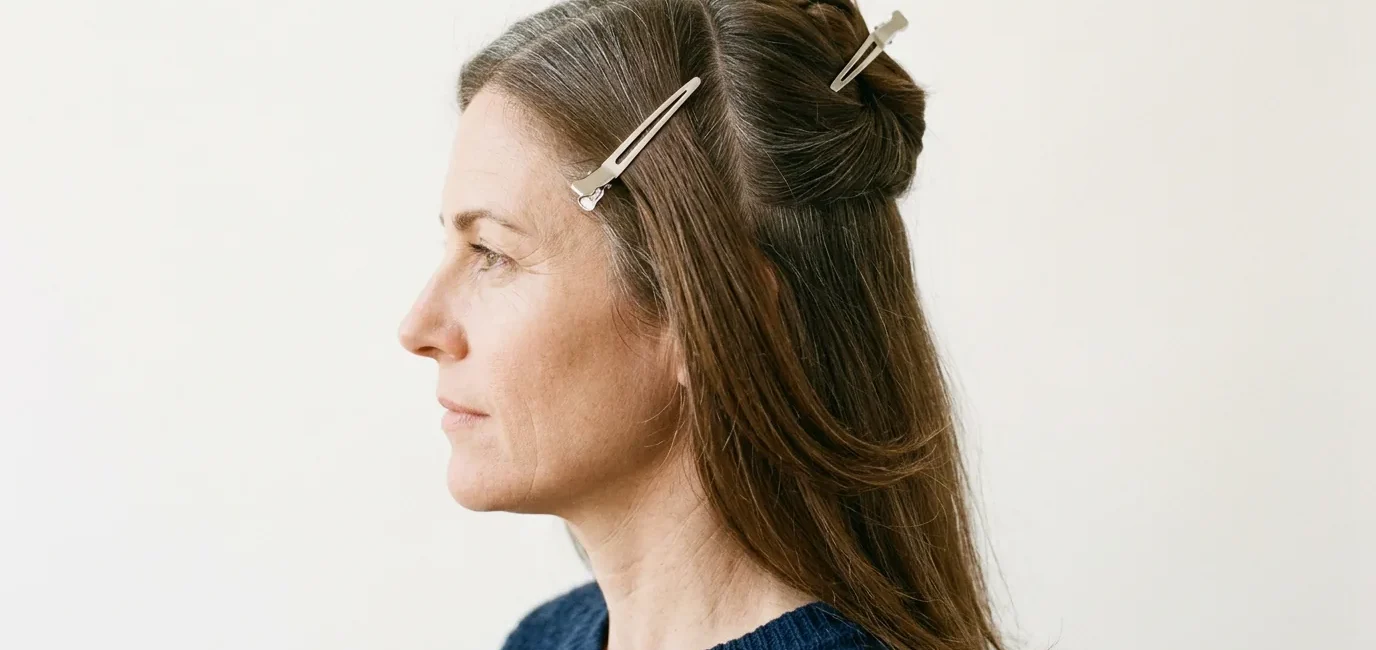 Woman with long brown hair sectioned into four quadrants with clips holding upper sections away from lower back panel