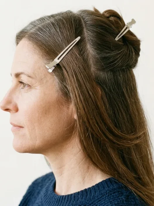 Woman with long brown hair sectioned into four quadrants with clips holding upper sections away from lower back panel