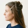Woman with long brown hair sectioned into four quadrants with clips holding upper sections away from lower back panel