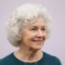 Seventy-two-year-old woman with soft rounded white curls against a pale lilac backdrop in gentle even light