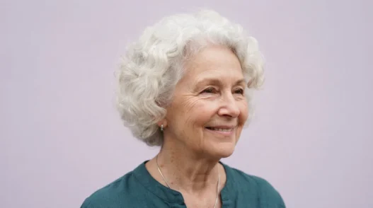 Elderly woman with soft white rounded curls against pale lilac backdrop in gentle even light