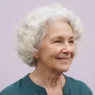 Elderly woman with soft white rounded curls against pale lilac backdrop in gentle even light